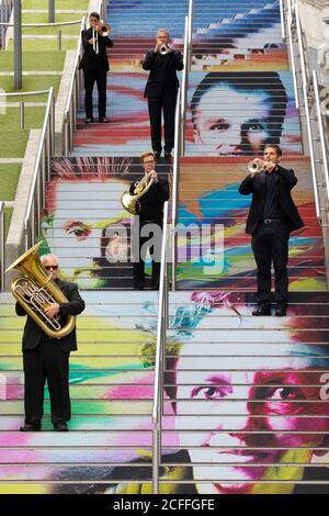 Les membres du public regardent une apparition surprise par un quintette en laiton de l'Orchestre philharmonique royal sur les marches espagnoles à Wembley Park. Banque D'Images