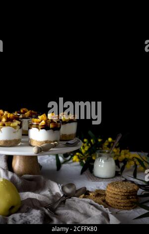 Assortiment de desserts délicieux et d'en-cas placés sur une table près de la serviette et fleurs sur fond noir Banque D'Images