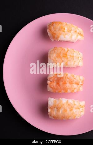 Vue de dessus de l'ensemble de sushis EBI Nigiri servis sur plaque sur fond sombre en studio Banque D'Images