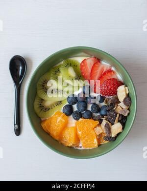 Du dessus de délicieux petit déjeuner sain avec des tranches de kiwi et oranges placées dans un bol avec des bleuets et des fraises Banque D'Images