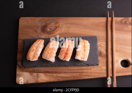 Vue de dessus de délicieux sushis avec riz et crevettes servis sur bois avec baguettes dans le restaurant Banque D'Images