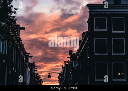 Faible angle de ciel brûlant avec coucher de soleil nuages colorés au-dessus Bâtiments d'Amsterdam d'âge sombre Banque D'Images