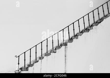 Escalier noir et blanc avec marches en béton et métal bannister sur fond de mur blanc Banque D'Images