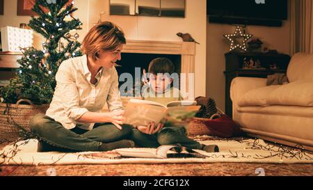 Mère lisant le livre avec son fils la veille de Noël Banque D'Images