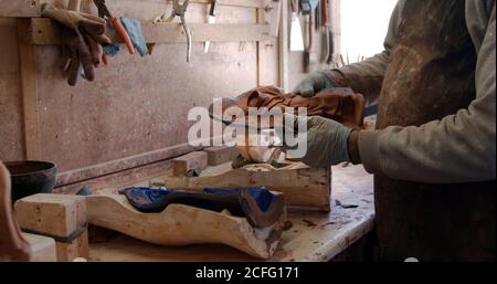 Vue latérale de Crop potter dans des gants et un tablier sales ouverture de la forme et obtenir la sculpture en argile sur la table en poterie Banque D'Images