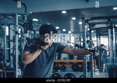 Un homme qui travaille sur sa poitrine avec Cable Crossover dans la salle de gym. Concept de fitness, d'entraînement, de sport et de santé. Banque D'Images