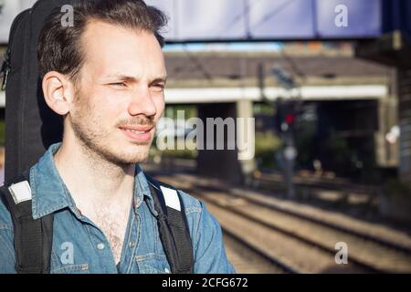 Portrait d'un jeune homme qui s'accroupse en train sur la plate-forme, en train de s'élancer dans la patience Banque D'Images