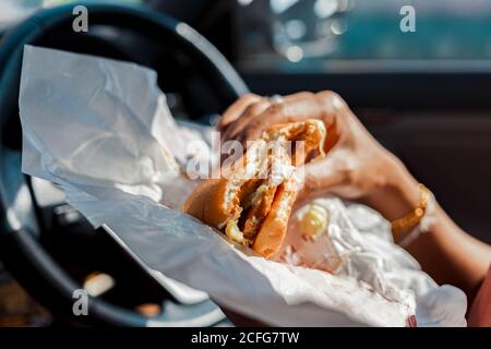 Homme mangeant un hamburger en voiture. Banque D'Images