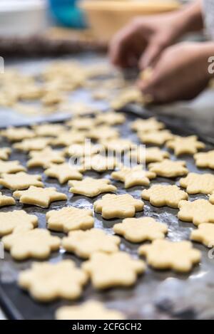 chef inreconnaissable coupant de petits biscuits à partir de pâte crue sur du métal table recouverte de farine dans la boulangerie Banque D'Images