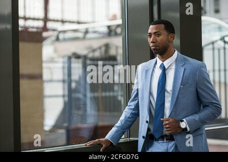 Jeune homme afro-américain portant un élégant costume bleu et regardant debout loin Banque D'Images