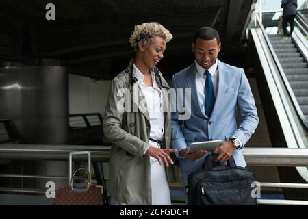 Joyeux homme et femme afro-américain élégant regardant la tablette ensemble et souriant. Banque D'Images