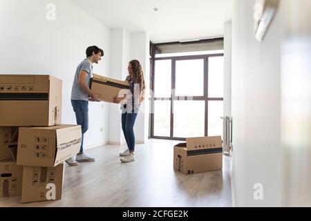 Jeune couple déballage dans un appartement vide avec beaucoup de boîtes en carton Banque D'Images