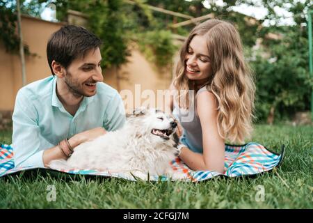 Couple heureux de gars jouant avec leur chien dans l'arrière-cour sur l'herbe. Vieux chien joyeux Banque D'Images