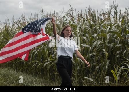 Une fille avec un drapeau américain marche le long d'un champ de maïs, Labor Day, Banque D'Images