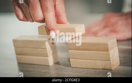 Femme construisant un pont à la main avec des blocs de bois; concept d'association Banque D'Images