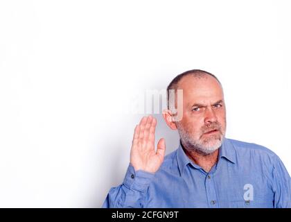 l'homme en chemise bleue mettant sa main près de lui oreille sur fond blanc Banque D'Images