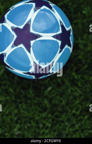 Ballon de football et marqueur à cône rouge sur le terrain d'entraînement. Gazon de football. Stade de football en arrière-plan flou. Jeunes joueurs pratiquant en arrière-plan Banque D'Images