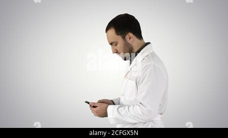 Gros plan portrait d'un beau professionnel de la santé ou d'un médecin ou d'une infirmière, textant sur un téléphone cellulaire sur fond de gradient. Banque D'Images