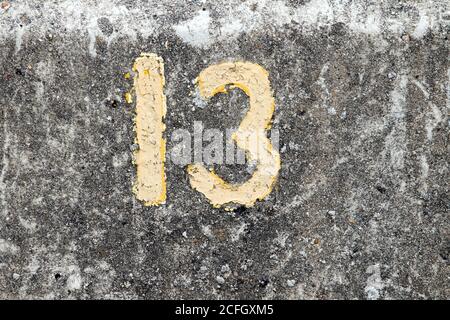 Numéro 13 de peinture jaune i=sur un mur de pierre de mer à Harwich, Essex, Royaume-Uni Banque D'Images