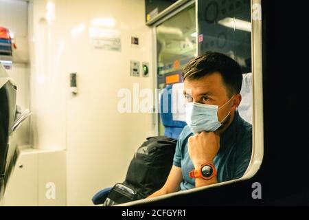 L'homme Sad porte un masque de protection dans le train pour protéger le système respiratoire de l'infection à coronavirus, Covid-19. Mesure préventive. Nouvelle normale. Déplacement Banque D'Images