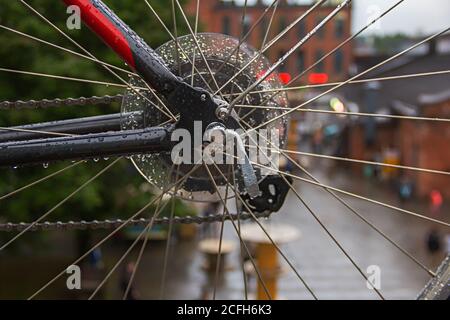 Vue en gros plan des pédales de vélo humides et du disque de frein avec la plaquette de frein de la roue arrière sur fond urbain Banque D'Images