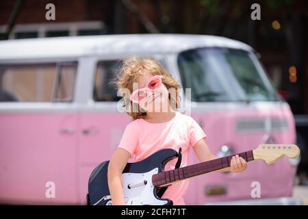 Enfant drôle avec guitare rock. Un petit garçon de campagne américain jouant de la musique. Banque D'Images