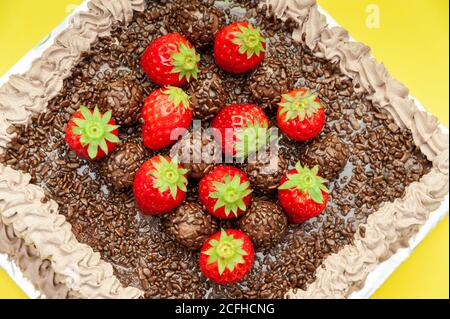 Gâteau au chocolat maison recouvert de saupoudriers au chocolat et de fraises fraîches. Connu au Brésil sous le nom de « Bolo de Brigadeiro ». Banque D'Images
