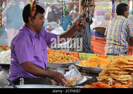 Un fournisseur mesurant les aliments sucrés traditionnels Jalebi/Jilapi dans un magasin d'un marché local. Il est populaire au Bangladesh et en Inde Banque D'Images