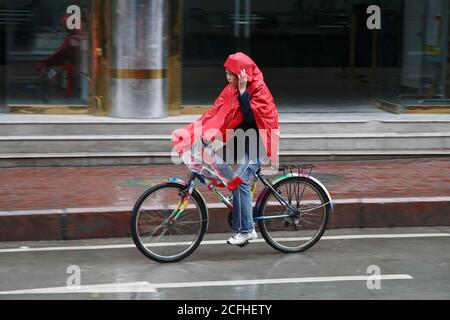 Femme cycliste en pluie, Rilong, Sichuan, Chine 26 juin 2006 Banque D'Images