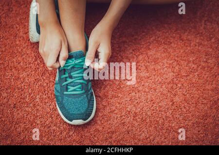 Jeune fille brune attrayante enlaçage ses chaussures de sport. Banque D'Images