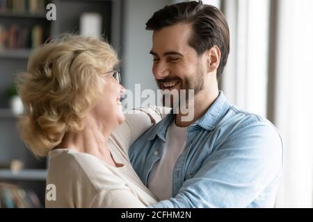 Gros plan souriant, mère et fils adultes qui s'embrasent Banque D'Images