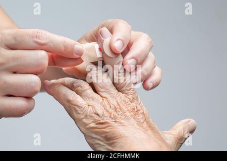Infirmière mettant le bandage adhésif sur la main de femme âgée Banque D'Images
