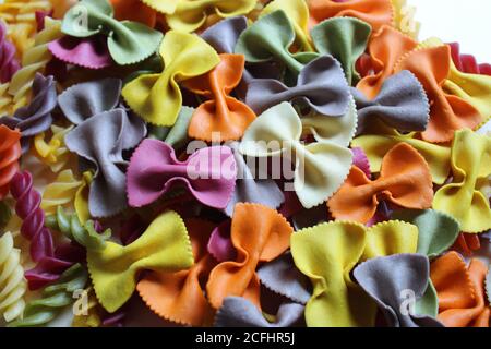 Mélange festif de farfalle multicolore et de pâtes fusilli sur un arrière-plan blanc Banque D'Images