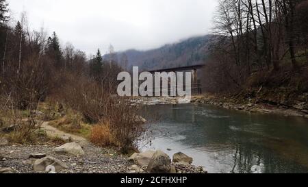 Vue sur le pont ferroviaire au-dessus de la rivière Prut. Une petite ville ou village de Yaremche parmi les Carpates un après-midi d'automne. Ukraine, Yaremcha - Banque D'Images