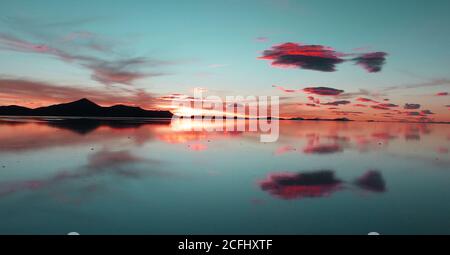 Coucher de soleil exceptionnel sur le lac Uyuni. Les nuages roses réfléchissent dans l'eau salée. Magnifique spectacle. Une vue inoubliable. Sérénité et méditation. Banque D'Images