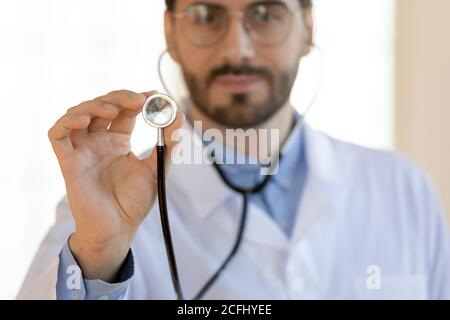 Gros plan jeune médecin sérieux tenant stéthoscope, concept de contrôle médical Banque D'Images