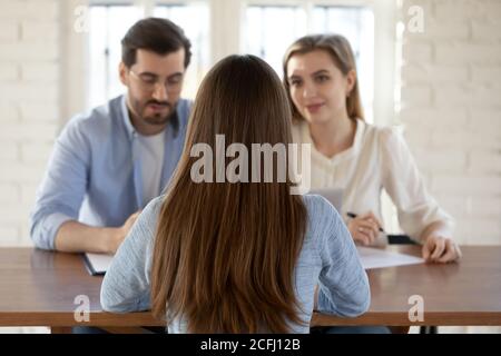 Vue arrière deux managers d'une heure interviewant la jeune femme candidate Banque D'Images