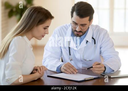 Médecin consultant une jeune femme au sujet des conditions ou des prescriptions du contrat d'assurance Banque D'Images