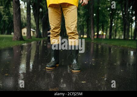 Homme en cape de pluie et bottes en caoutchouc Banque D'Images