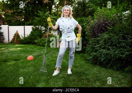 Femme souriante avec travaux de râteau dans le jardin Banque D'Images