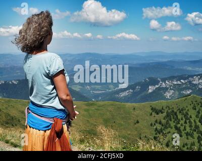 LITTLE FATRA, SLOVAQUIE - 08/03/2018: Femme hippie caucasienne en longue jupe orange randonnée dans le parc national de Little Fatra et vue sur l'horizon. Banque D'Images