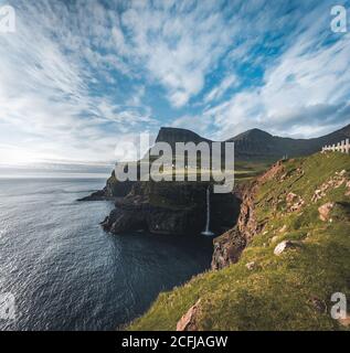 Le village de Gasadalur et Mulafossur sa chute d'eau emblématique pendant l'été avec le ciel bleu. Gélose, Îles Féroé, Danemark. Voir rugueux dans l'atlantique nord Banque D'Images