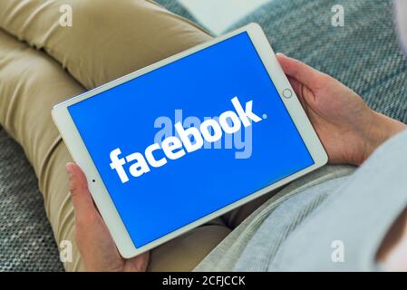 Femme mains utilisant l'iPad avec la page d'accueil Facebook à l'écran. Facebook le plus grand site de réseaux sociaux. Banque D'Images