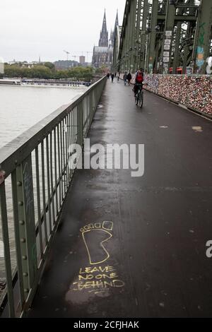 graffiti 'ne laissez personne derrière' sur le pont de chemin de fer Hohenzollern, vue sur la cathédrale, Cologne, Allemagne. Graffitis « ne laissez personne derrière vous » auf der Banque D'Images