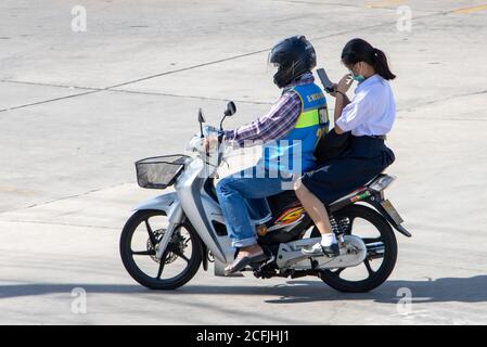 SAMUT PRAKAN, THAÏLANDE, JUL 01 2020, UN chauffeur de taxi sur une moto manèges avec une fille en uniforme scolaire. Le chauffeur de moto-taxi transporte un étudiant qui regarde t Banque D'Images