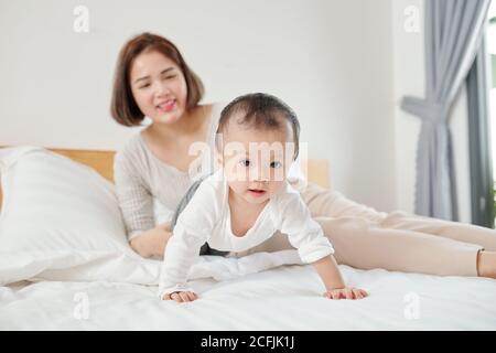 Mère regardant bébé rampant Banque D'Images