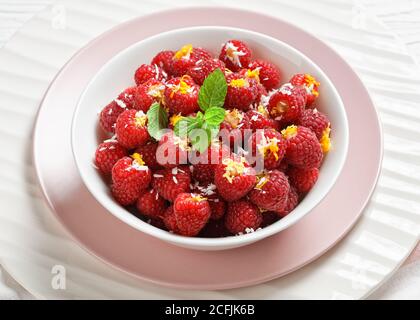 Des roquette de framboises farcies fraîches de framboises crues remplies de noix de coco râpée et de zeste d'orange servies sur des assiettes blanches et roses à la menthe fraîche, près Banque D'Images