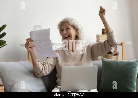 Une femme mûre surjoyée lisant les bonnes nouvelles dans la lettre, tenant des papiers Banque D'Images