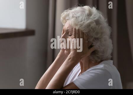 Gros plan frustré épuisé femme mature touchant les temples, sensation de douleur Banque D'Images
