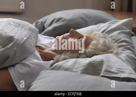 Gros plan calme décontracté femme adulte dormant dans un lit confortable Banque D'Images